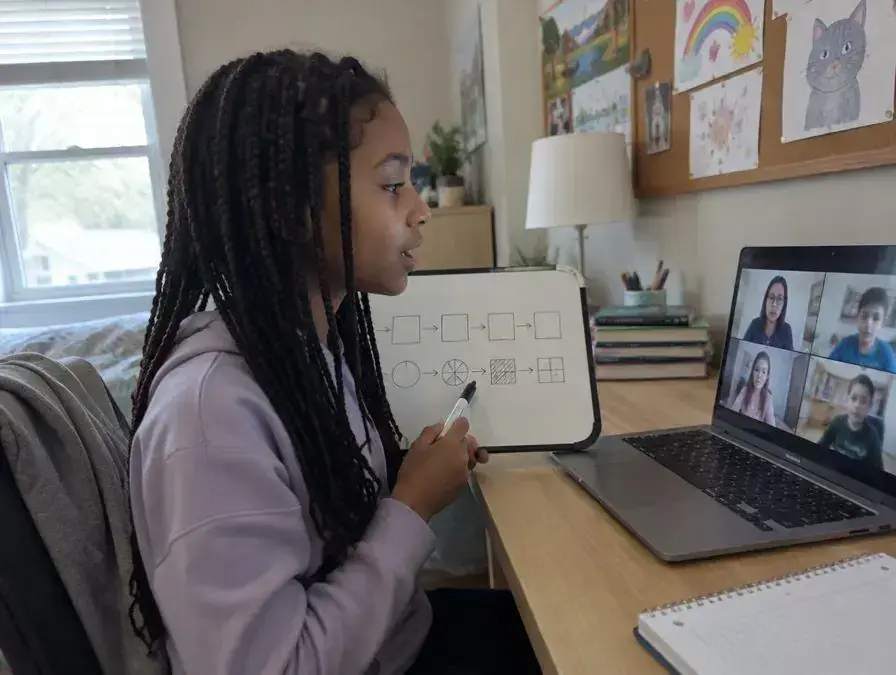 A girl explains an idea on a small whiteboard while her dad listens