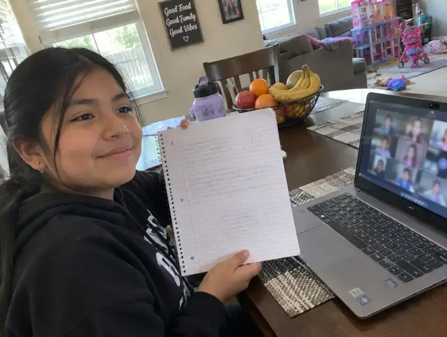 A girl explains an idea on a small whiteboard while her dad listens