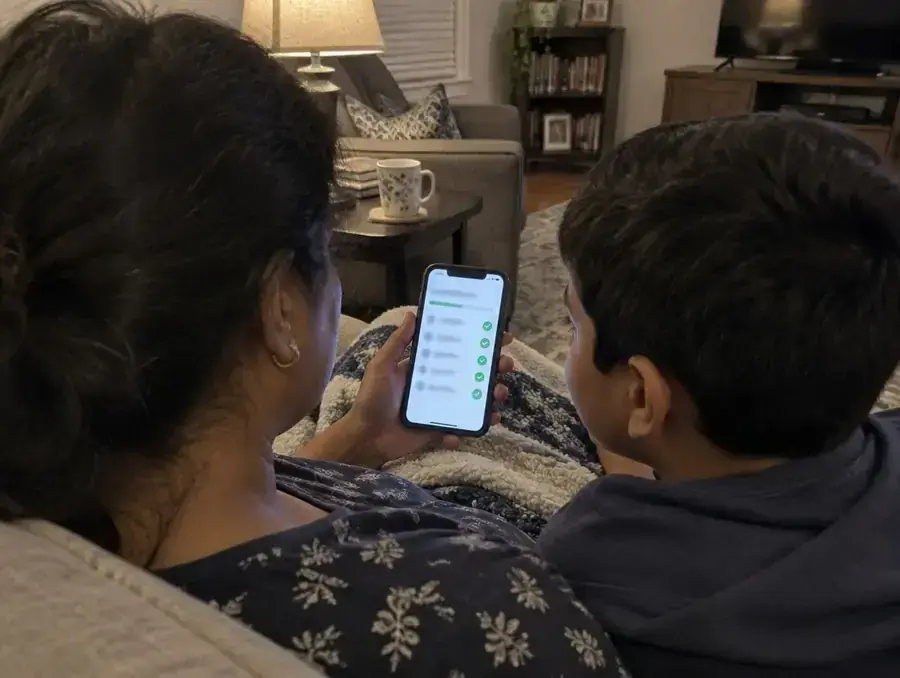 A mother and son look at a monthly progress report on her phone