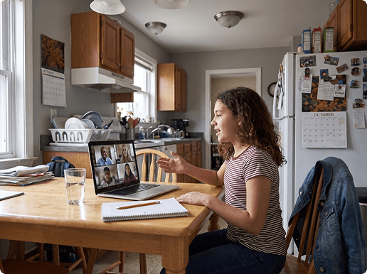 The same girl at her own kitchen table, talking and gesturing at a laptop showing her teacher and three classmates.