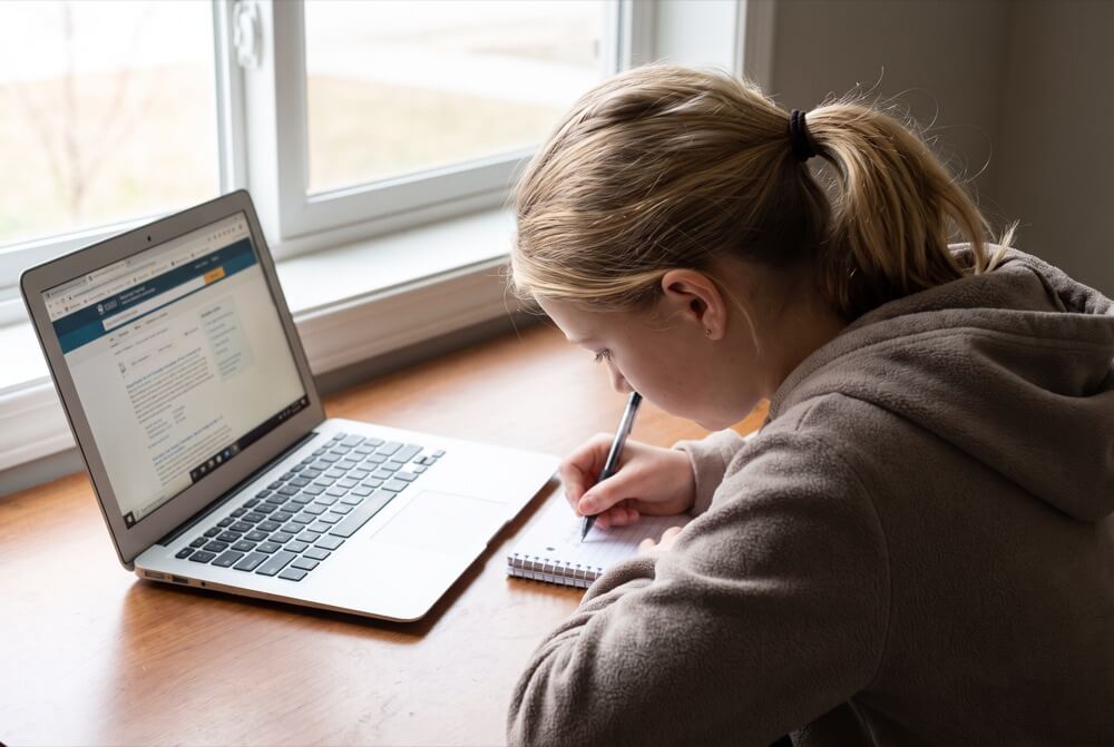 A student sits very still over a test paper, concentrating hard.